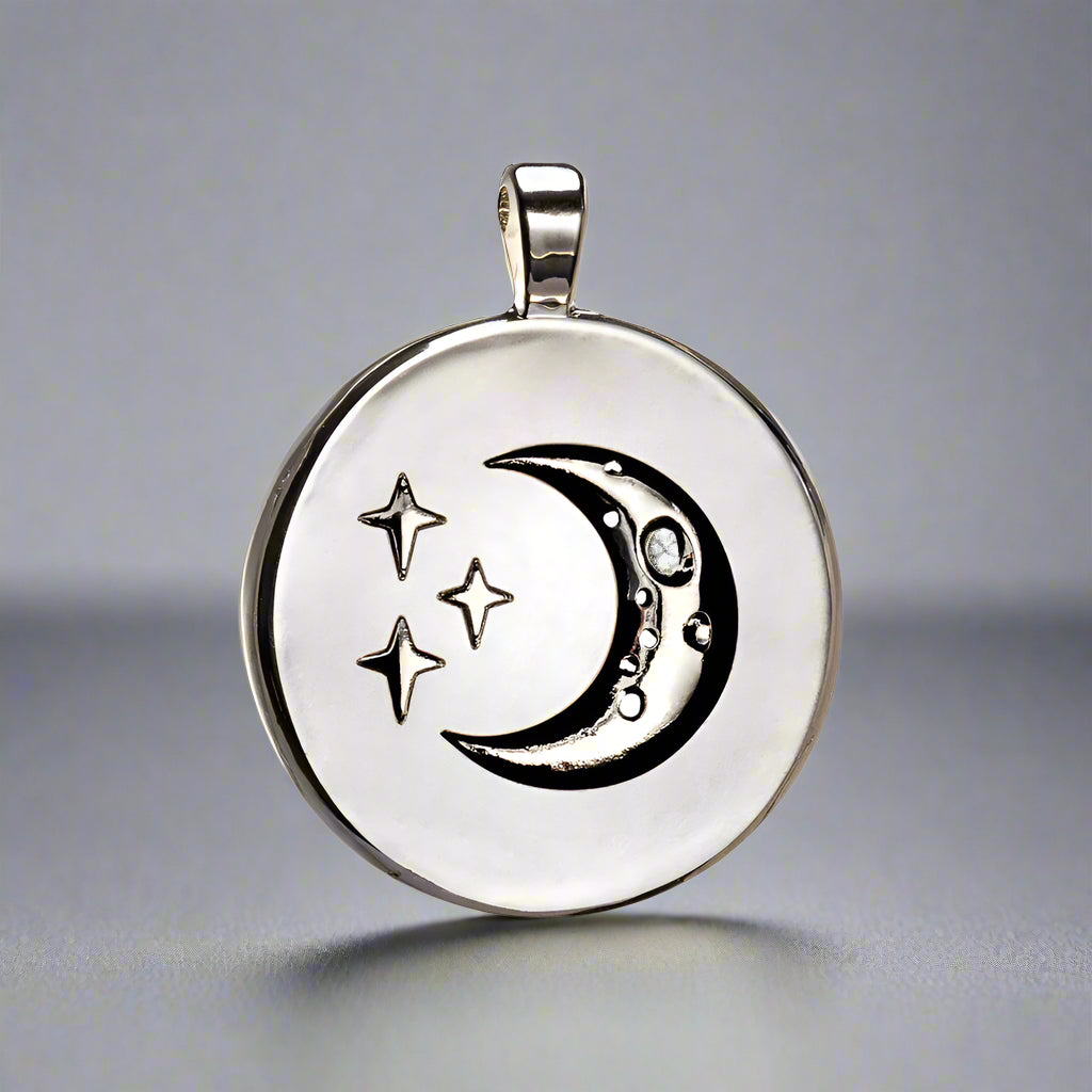Silver pendant with moon and star designs on a white background