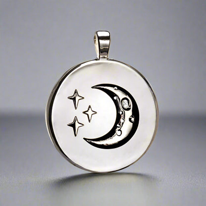 Silver pendant with moon and star designs on a white background
